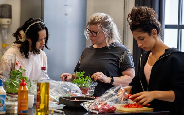 Foto van coach en jongeren tijdens het koken